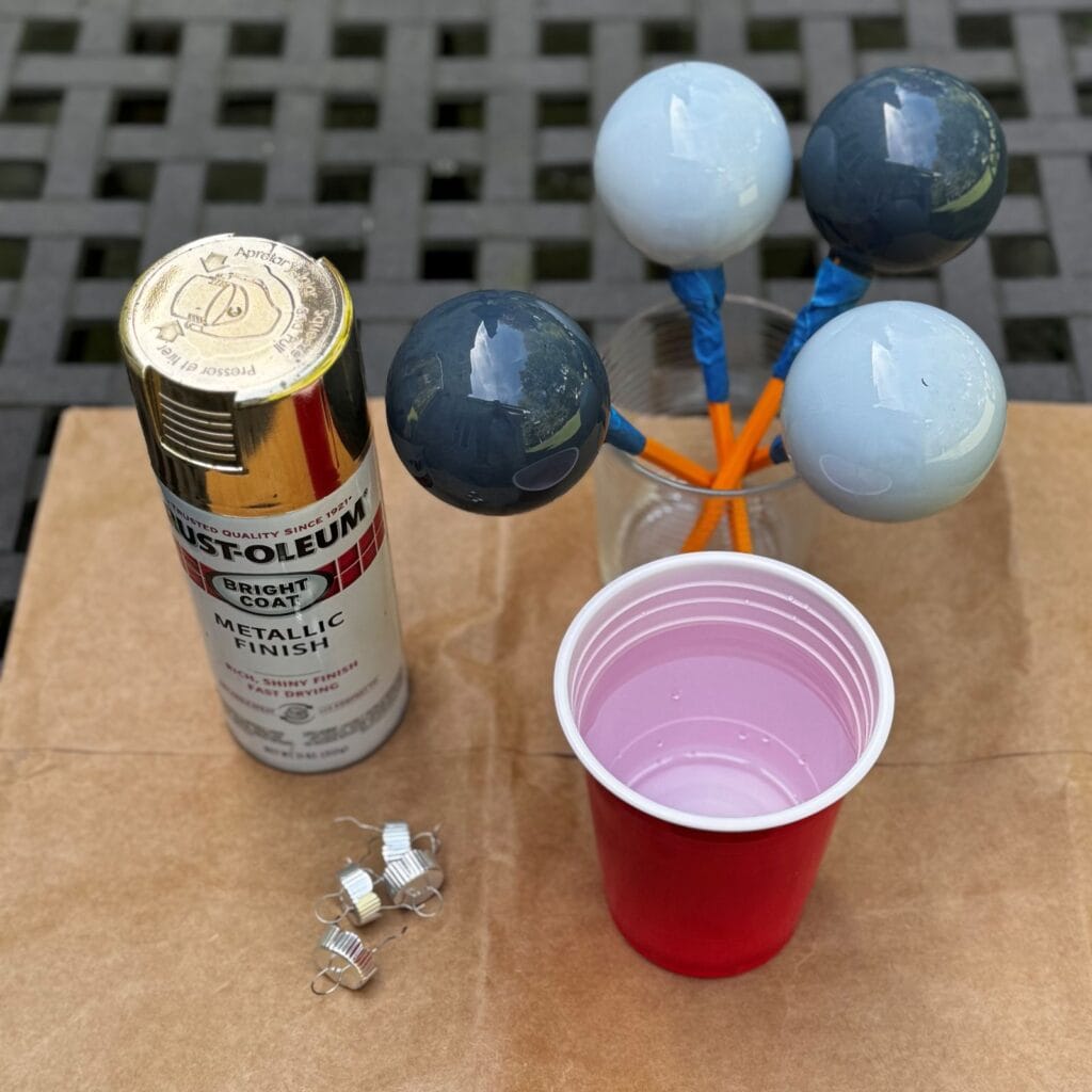 Photo of glass ornaments painted light and dark blue, with some spray paint next to the them.