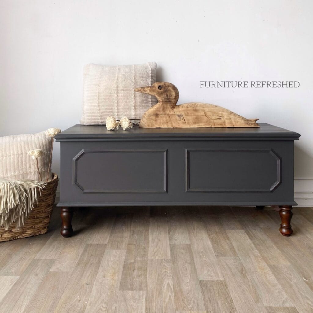 Cedar chest painted in dark gray paint with dark wood stained legs.