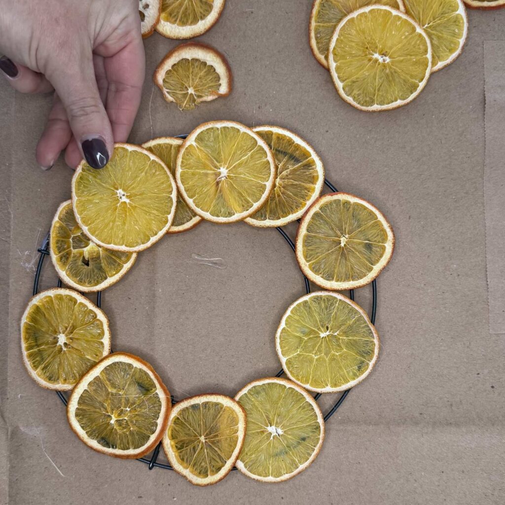 Gluing a second layer of oranges to the wreath.