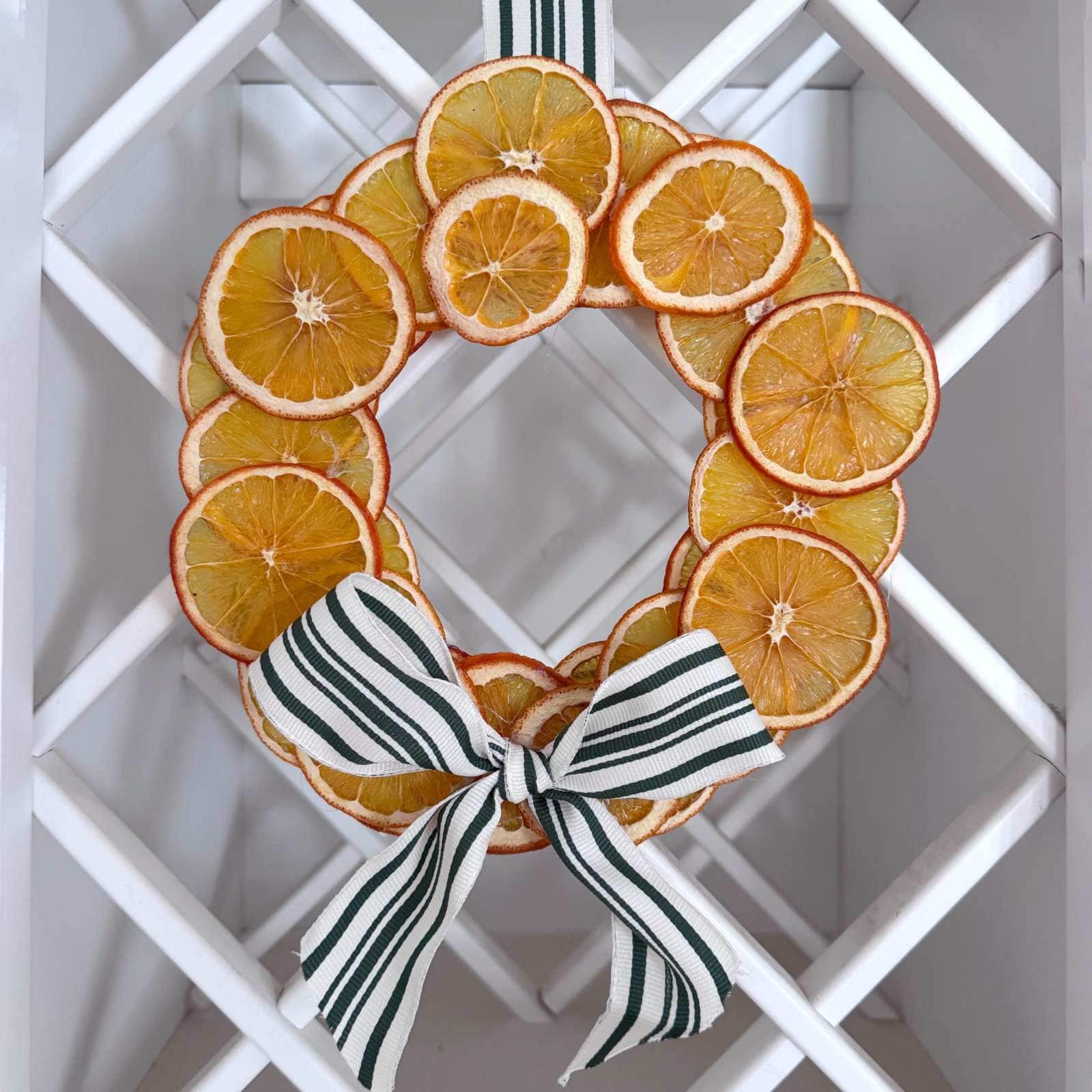 Photo of completed dried orange wreath with a white and green bow.
