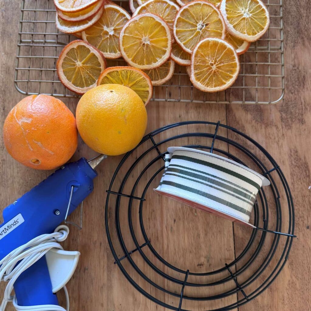 Supplies used for this project. Includes, wire wreath fram, ribbon, glue gun and oranges.