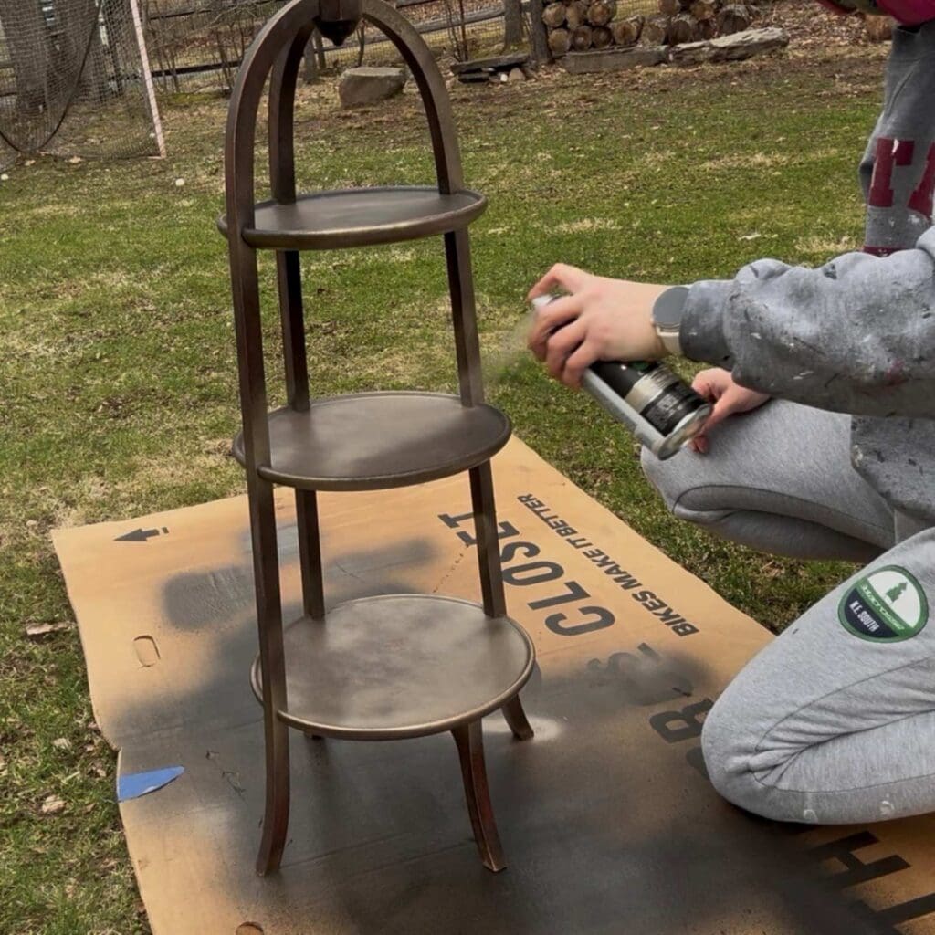 Painting the first coat of metallic spray paint on the plant stand.
