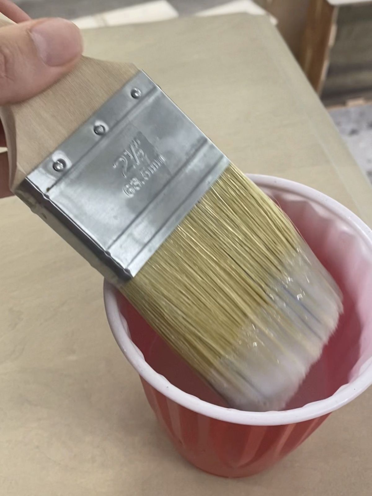 Brush being dipped into top coat for application on the dresser.